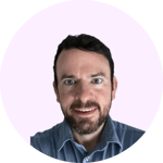 The image shows a headshot of a man with short dark hair and a beard, wearing a navy blue shirt. He has a friendly, open expression and is looking directly at the camera.