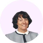 The image shows a headshot of a smiling Woman with short, dark hair wearing a gray collared shirt against a light pink background.