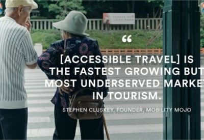 The image shows two people standing in front of a sign that displays a quote about accessible travel being the fastest growing but most underserved market in tourism.