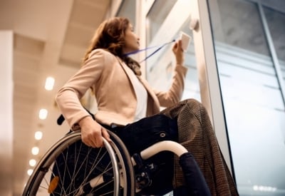 A wheelchair user opening a glass door with a keycard.