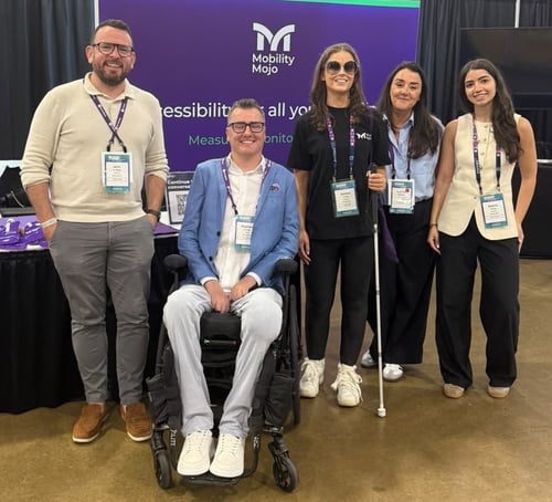 The Mobility Mojo team smiling together at their stand at a conference