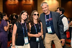 Two Mobility Mojo team members smiling with Frank Justus from Bayer at a conference
