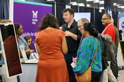 A busy Mobility Mojo stand at a conference, with a team member talking visitors through the platform