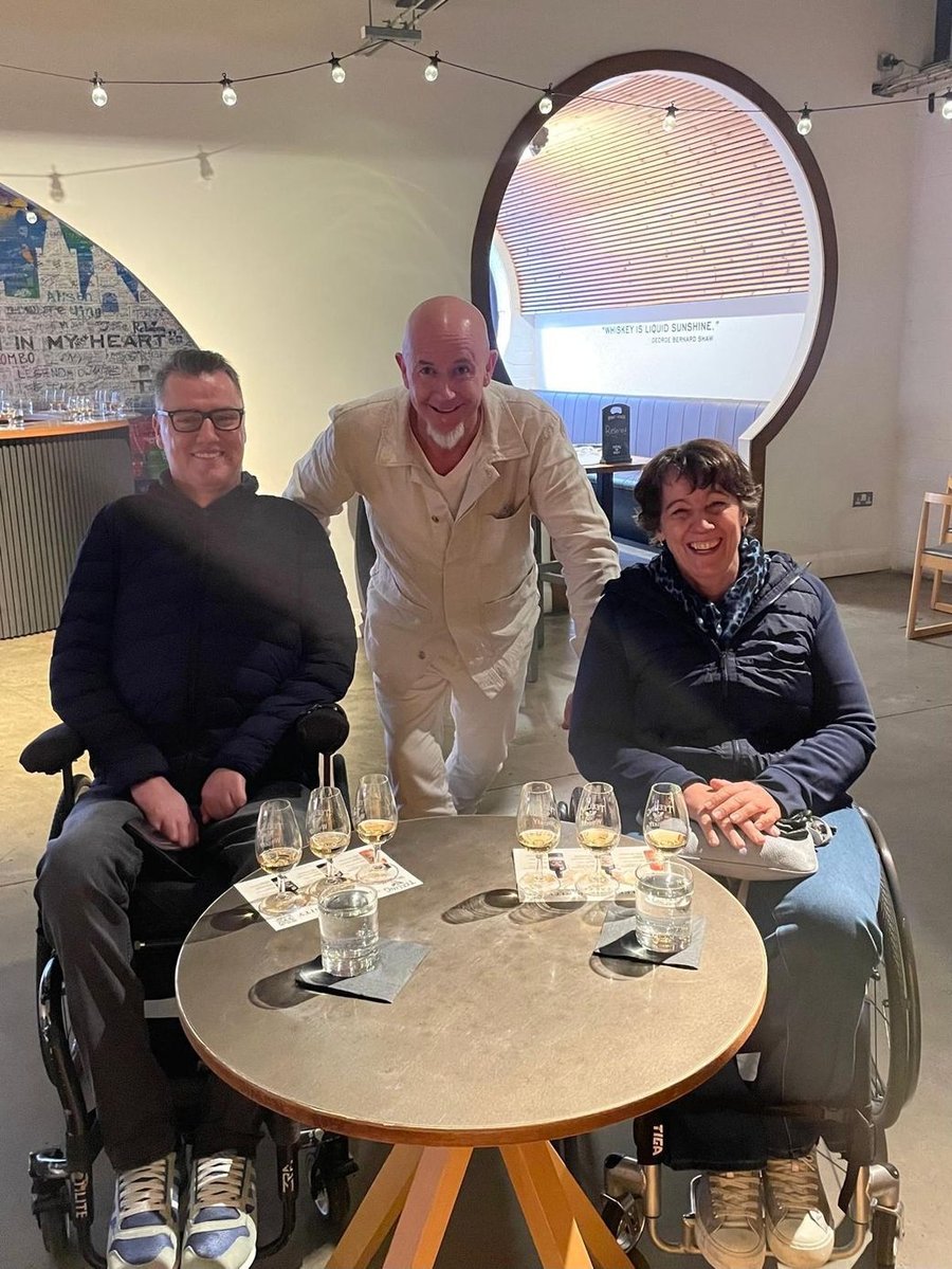 The Mobility Mojo founders around a tasting table — Stephen and Noelle in their wheelchairs, Patrick standing between them