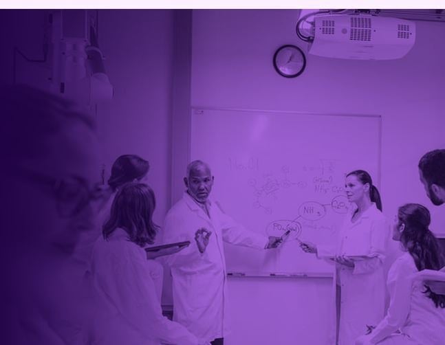 Scientists in lab coats collaborating at a whiteboard in a laboratory