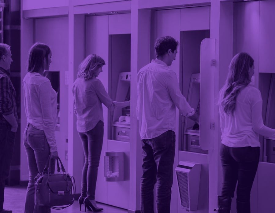 Customers using a row of ATMs in a retail bank branch