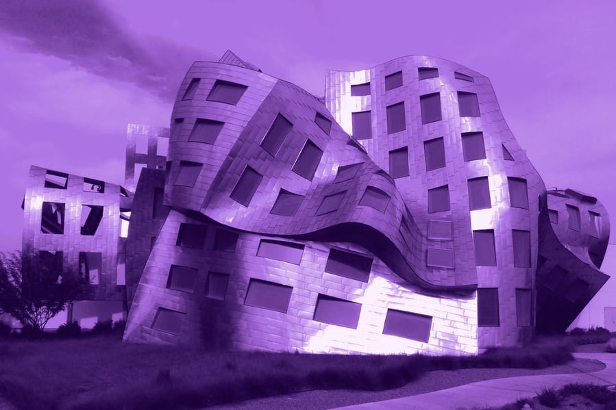 A sculptural metal-clad building with curved walls, no two windows aligned the same way