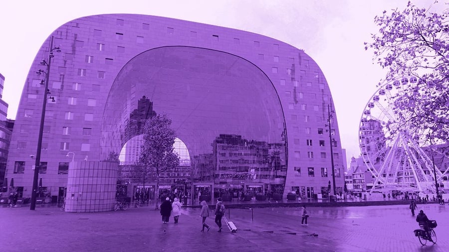 A horseshoe-shaped market hall with a vast glazed arch, people crossing the square in front