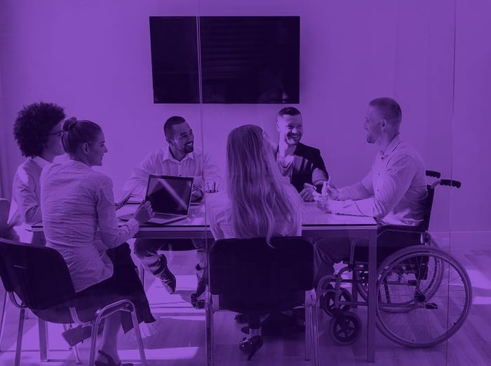 Colleagues in an office meeting, one a wheelchair user